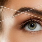 Jeune femme en train de se faire épiler le sourcil au fil.
